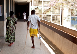 A young man with a leg amputation walks the corridors of Mulago Hospital